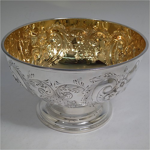 A very pretty Antique Edwardian Sterling Silver large table bowl, having a round body with an applied reeded border and hand-chased floral and scroll decoration, with two vacant cartouches either side, a gold-gilt interior, and all sitting on a stepped pedestal foot. Made by the Deakin Brothers of Sheffield in 1904. The dimensions of this fine hand-made antique silver bowl are diameter 25.5 cms (10 inches), height 15 cms (6 inches), and it weighs approx. 780g (25 troy ounces).