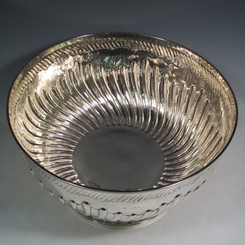 Antique Victorian sterling silver large Rose bowl, having a round body with hand-chased half swirl-fluted decoration, an applied reeded rim above another band of hand-chased fluting, and sitting on a pedestal foot with matching fluting. Made by Lamberts of London in 1893. The dimensions of this fine hand-made silver large table bowl are diameter 35 cms (13.75 inches), height 21 cms (8.25 inches), and it weighs approx. 1,767g (57 troy ounces).