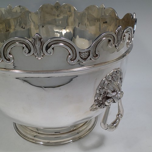 A very handsome and large Antique Edwardian Sterling Silver Montieth style bowl, having a plain round body with an applied scroll border, together with two cast lion-mask side-handles, and sitting on a pedestal foot. Made by William Comyns of London in 1902. The dimensions of this fine hand-made antique silver Montieth table bowl are diameter 31 cms (12 inches), height 23 cms (9 inches), and it weighs approx. 2,440g (78.7 troy ounces).