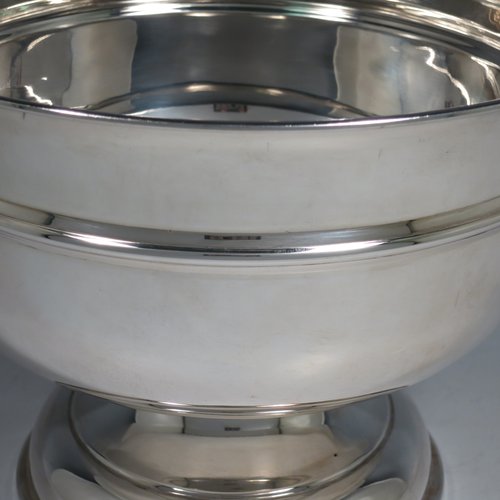 A Sterling Silver table bowl, having a round plain body, with an applied central band, and sitting on a matching pedestal foot. Made in Birmingham in 1930. The dimensions of this fine hand-made silver bowl are diameter 24 cms (9.5 inches), height 18.5 cms (7.25 inches), and it weighs approx. 807g (26 troy ounces).