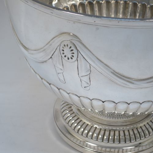 A very pretty Antique Victorian Sterling Silver large Rose bowl, having a round body with hand-chased half fluted decoration, an applied reeded rim above another band of hand-chased swags and bows, and sitting on a pedestal foot with matching fluting. Made by Gibson and Langman of London in 1890. The dimensions of this fine hand-made antique silver large table bowl are diameter 24 cms (9.5 inches), height 20 cms (8 inches), and it weighs approx. 965g (31 troy ounces).