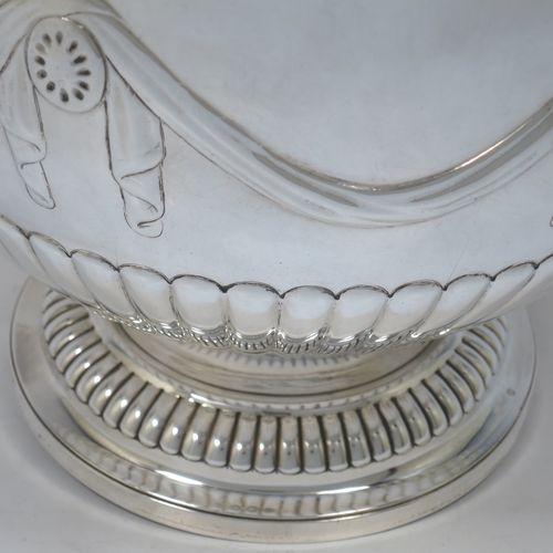 A very pretty Antique Victorian Sterling Silver large Rose bowl, having a round body with hand-chased half fluted decoration, an applied reeded rim above another band of hand-chased swags and bows, and sitting on a pedestal foot with matching fluting. Made by Gibson and Langman of London in 1890. The dimensions of this fine hand-made antique silver large table bowl are diameter 24 cms (9.5 inches), height 20 cms (8 inches), and it weighs approx. 965g (31 troy ounces).