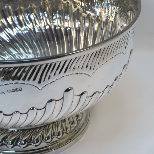 A rare and very large Antique late Georgian Sterling Silver table bowl, having a round body with an applied reeded top border and hand-chased half swirl-fluted decoration, all sitting on a pedestal foot which is also fluted. This large and handsome antique silver bowl was made by Thomas Barker of London in 1822. The dimensions of this fine hand-made antique silver bowl are diameter 35 cms (13.75 inches), height 19.5 cms (7.75 inches), and it weighs approx. 1,980g (63.9 troy ounces). Please note that this item has a full armorial crest on both sides.