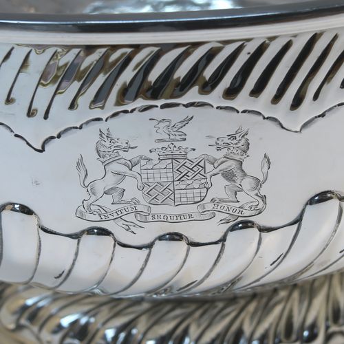 A rare and very large Antique late Georgian Sterling Silver table bowl, having a round body with an applied reeded top border and hand-chased half swirl-fluted decoration, all sitting on a pedestal foot which is also fluted. This large and handsome antique silver bowl was made by Thomas Barker of London in 1822. The dimensions of this fine hand-made antique silver bowl are diameter 35 cms (13.75 inches), height 19.5 cms (7.75 inches), and it weighs approx. 1,980g (63.9 troy ounces). Please note that this item has a full armorial crest on both sides.