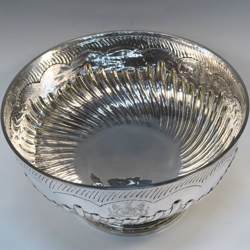 A rare and very large Antique late Georgian Sterling Silver table bowl, having a round body with an applied reeded top border and hand-chased half swirl-fluted decoration, all sitting on a pedestal foot which is also fluted. This large and handsome antique silver bowl was made by Thomas Barker of London in 1822. The dimensions of this fine hand-made antique silver bowl are diameter 35 cms (13.75 inches), height 19.5 cms (7.75 inches), and it weighs approx. 1,980g (63.9 troy ounces). Please note that this item has a full armorial crest on both sides.