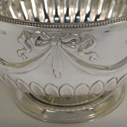A very pretty Antique Edwardian Sterling Silver large Rose bowl, having a round body with hand-chased half fluted decoration, an applied bead-edged top border above another band of hand-chased swags and bows, and sitting on a pedestal foot with matching border. This beautiful antique silver bowl was made by William Hutton of Sheffield in 1902. The dimensions of this fine hand-made antique silver large table bowl are diameter 23 cms (9 inches), height 14.5 cms (5.75 inches), and it weighs approx. 620g (20 troy ounces).