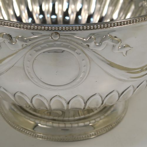 A very pretty Antique Edwardian Sterling Silver large Rose bowl, having a round body with hand-chased half fluted decoration, an applied bead-edged top border above another band of hand-chased swags and bows, and sitting on a pedestal foot with matching border. This beautiful antique silver bowl was made by William Hutton of Sheffield in 1902. The dimensions of this fine hand-made antique silver large table bowl are diameter 23 cms (9 inches), height 14.5 cms (5.75 inches), and it weighs approx. 620g (20 troy ounces).