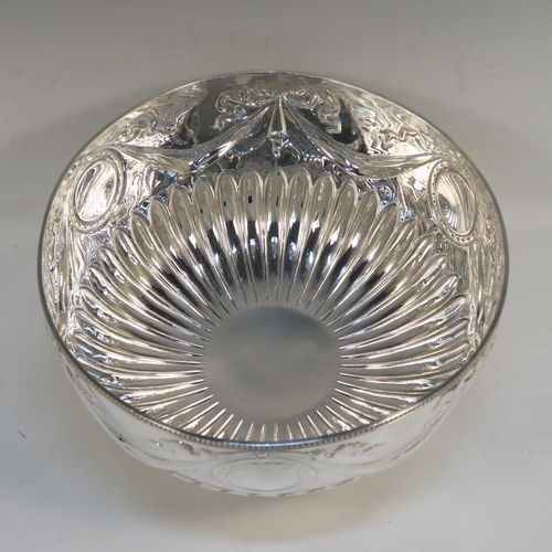 A very pretty Antique Edwardian Sterling Silver large Rose bowl, having a round body with hand-chased half fluted decoration, an applied bead-edged top border above another band of hand-chased swags and bows, and sitting on a pedestal foot with matching border. This beautiful antique silver bowl was made by William Hutton of Sheffield in 1902. The dimensions of this fine hand-made antique silver large table bowl are diameter 23 cms (9 inches), height 14.5 cms (5.75 inches), and it weighs approx. 620g (20 troy ounces).