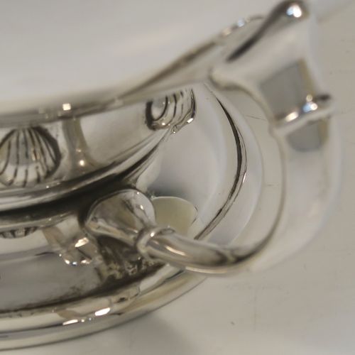 A very handsome Sterling Silver Art Deco style table bowl, having a plain round and bellied body, with four cast scroll supports attached to a pedestal foot with a central girdle of applied shell motifs. This elegant silver table bowl was made by James Ogden and Sons of Birmingham in 1934. The dimensions of this fine hand-made Art Deco silver bowl are height 15 cms (6 inches), diameter at top of bowl 20 cms (8 inches), and it weighs approx. 918g (29.6 troy ounces).
