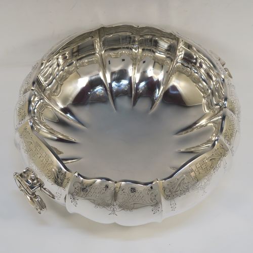 A very pretty and unusual Sterling Silver table bowl, having a round bellied body with a hand-engraved upper border showing scroll and floral decoration over hand-chased melon fluting, with two cast and hinged side handles, and all sitting on a pedestal foot. This beautiful silver bowl was made by Mappin and Webb of Sheffield in 1934. The dimensions of this fine hand-made silver bowl are diameter 25.5 cms (10 inches), height 12.5 cms (5 inches), and it weighs approx. 1,304g (42 troy ounces).  