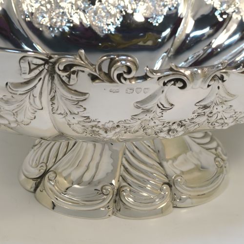 A very pretty and rare Antique Victorian Sterling Silver large oval Rose bowl, having an oval body with hand-chased fluting and garlands of floral decoration, an applied cast scroll top border, and sitting on a pedestal foot with matching decoration. This beautiful antique silver bowl was made by John Newton Mappin of London in 1894. The dimensions of this fine hand-made antique silver large table bowl are length 38 cms (15 inches), width 24 cms (9.5 inches), height 18.5 cms (7.25 inches), and it weighs approx. 1,203g (39 troy ounces).