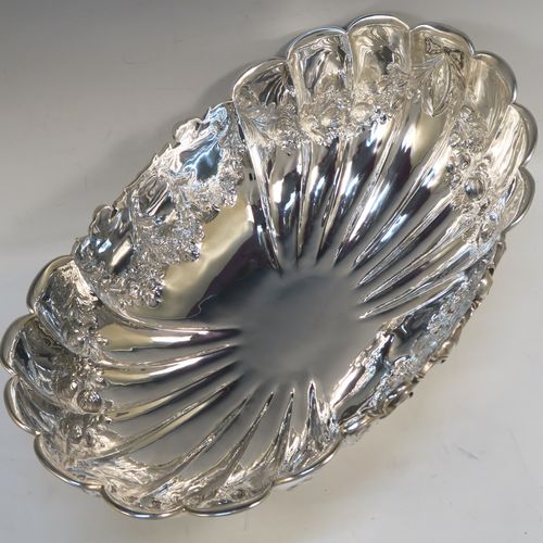 A very pretty and rare Antique Victorian Sterling Silver large oval Rose bowl, having an oval body with hand-chased fluting and garlands of floral decoration, an applied cast scroll top border, and sitting on a pedestal foot with matching decoration. This beautiful antique silver bowl was made by John Newton Mappin of London in 1894. The dimensions of this fine hand-made antique silver large table bowl are length 38 cms (15 inches), width 24 cms (9.5 inches), height 18.5 cms (7.25 inches), and it weighs approx. 1,203g (39 troy ounces).