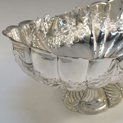 A very pretty and rare Antique Victorian Sterling Silver large oval Rose bowl, having an oval body with hand-chased fluting and garlands of floral decoration, an applied cast scroll top border, and sitting on a pedestal foot with matching decoration. This beautiful antique silver bowl was made by John Newton Mappin of London in 1894. The dimensions of this fine hand-made antique silver large table bowl are length 38 cms (15 inches), width 24 cms (9.5 inches), height 18.5 cms (7.25 inches), and it weighs approx. 1,203g (39 troy ounces).