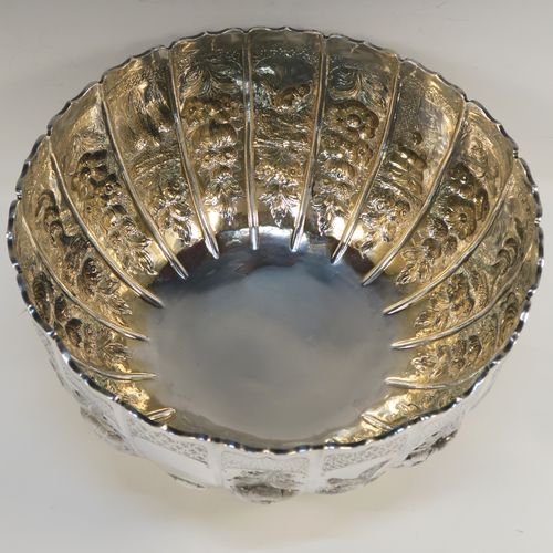 A very unusual and beautiful Antique Victorian Sterling Silver large Rose bowl, having a round panelled body with hand-chased floral and figural decoration, a wavy-edge top border and a gold-gilt interior, and all sitting on a round pedestal foot. This amazing antique silver bowl was made by Francis Boone Thomas of London in 1899. The dimensions of this fine hand-made antique silver large table bowl are diameter 30 cms (11.75 inches), height 17cms (6.75 inches), and it weighs approx. 1,286g (41.5 troy ounces).   
