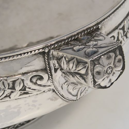 A very unusual and beautiful Antique Sterling Silver Art and Crafts style table bowl, having a round bellied body with hand-hammered decoration, an applied rope-twist top border, together with an applied central band of leaf design work, with three matching side-handles, and all sitting on a pedestal foot. This superb Arts and Crafts style silver table bowl was made by John Sydney Reeve of Birmingham in 1912. The dimensions of this fine hand-made antique silver bowl are height 8.5 cms (3.3 inches), diameter at top of bowl 24 cms (9.5 inches), and it weighs approx. 799g (25.8 troy ounces).