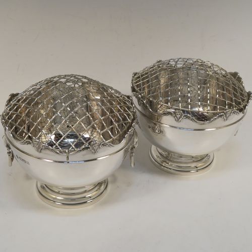 A handsome pair of Antique Edwardian Sterling Silver Monteith style bowls with rose grills, having round bodies with applied scroll borders, with cast lion-mask handles either side, and all sitting on pedestal feet. These elegant silver rose bowls were made by Jays of Chester in 1906. The dimensions of these fine hand-made antique silver Montieth rose bowls are diameter 14 cms (5.5 inches), height 11 cms (4.25 inches), and they weigh a total of approx. 800g (25.8 troy ounces). Please note that this item is part-crested.  