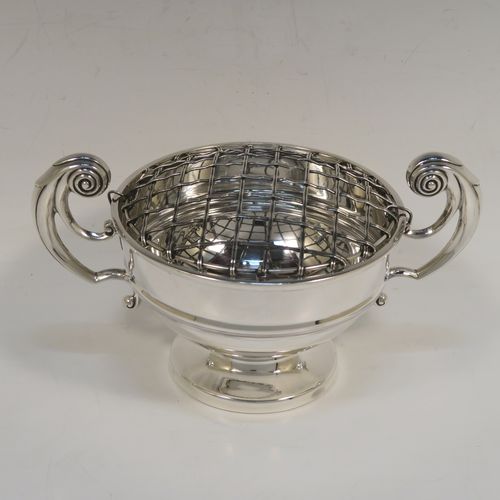A handsome classical style Sterling Silver Rose bowl, having a round plain body with an applied reeded border, and a central applied band, with two flying scroll side handles, and sitting on a round pedestal foot, together with its original metal rose grill. This elegant silver rose bowl was made by Walker and Hall of Sheffield in 1934. The dimensions of this fine hand-made silver two-handled bowl are height (inc. handles) 11 cms (4.3 inches), diameter 12.5 cms (5 inches), and it weighs approx. 300g (9.7 troy ounces).   