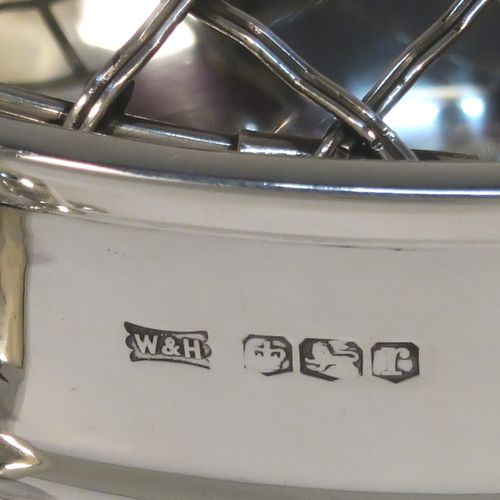 A handsome classical style Sterling Silver Rose bowl, having a round plain body with an applied reeded border, and a central applied band, with two flying scroll side handles, and sitting on a round pedestal foot, together with its original metal rose grill. This elegant silver rose bowl was made by Walker and Hall of Sheffield in 1934. The dimensions of this fine hand-made silver two-handled bowl are height (inc. handles) 11 cms (4.3 inches), diameter 12.5 cms (5 inches), and it weighs approx. 300g (9.7 troy ounces).