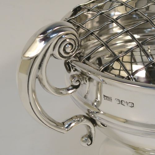 A handsome classical style Sterling Silver Rose bowl, having a round plain body with an applied reeded border, and a central applied band, with two flying scroll side handles, and sitting on a round pedestal foot, together with its original metal rose grill. This elegant silver rose bowl was made by Walker and Hall of Sheffield in 1934. The dimensions of this fine hand-made silver two-handled bowl are height (inc. handles) 11 cms (4.3 inches), diameter 12.5 cms (5 inches), and it weighs approx. 300g (9.7 troy ounces).