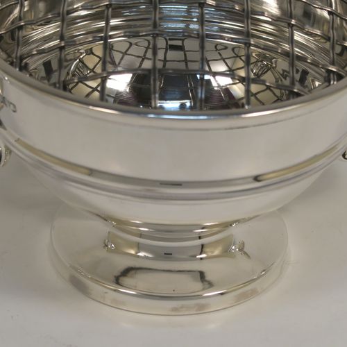 A handsome classical style Sterling Silver Rose bowl, having a round plain body with an applied reeded border, and a central applied band, with two flying scroll side handles, and sitting on a round pedestal foot, together with its original metal rose grill. This elegant silver rose bowl was made by Walker and Hall of Sheffield in 1934. The dimensions of this fine hand-made silver two-handled bowl are height (inc. handles) 11 cms (4.3 inches), diameter 12.5 cms (5 inches), and it weighs approx. 300g (9.7 troy ounces).