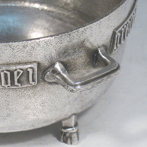 An Antique Edwardian Sterling Silver Arts & Crafts style bowl, being a copy of the Winchester Bushel measure, having a round straight-sided body with a hand-hammered finish, an applied inscription on both sides, with two cast handles, and sitting on four cast feet. Made by the Barnard Brothers of London in 1905. The dimensions of this fine hand-made antique silver bowl are height 8 cms (2.3 inches), diameter 11.5 cms (4.5 inches), and it weighs approx. 325g (10.5 troy ounces).