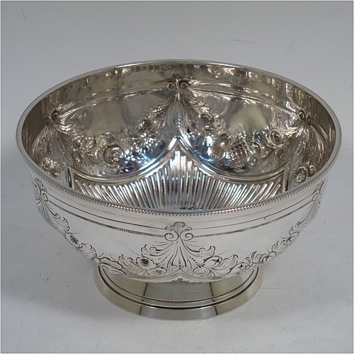 A very pretty Antique Victorian Sterling Silver bowl, having a round body with hand-chased swags of floral and scroll decoration over a lower band of vertical fluting, with an applied bead-edged border, and all sitting on a collet foot. Made by Edward Hutton of London in 1885. The dimensions of this fine hand-made antique silver bowl are diameter 11 cms (4.3 inches), height 6 cms (2.3 inches), and it weighs approx. 140g (4.5 troy ounces).    