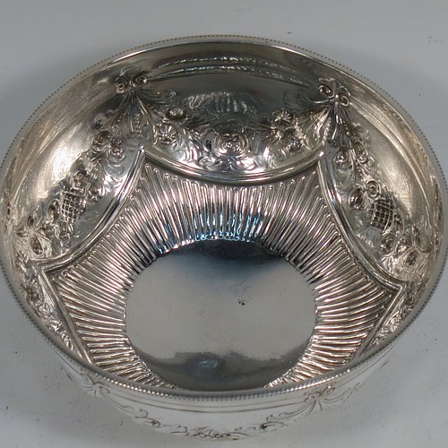 A very pretty Antique Victorian Sterling Silver bowl, having a round body with hand-chased swags of floral and scroll decoration over a lower band of vertical fluting, with an applied bead-edged border, and all sitting on a collet foot. Made by Edward Hutton of London in 1885. The dimensions of this fine hand-made antique silver bowl are diameter 11 cms (4.3 inches), height 6 cms (2.3 inches), and it weighs approx. 140g (4.5 troy ounces).