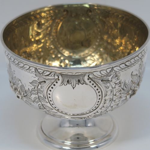A very pretty Antique Victorian Sterling Silver rose bowl, having a round body with hand-chased swags of floral decoration surrounding two vacant round cartouches on either side, with an applied reed-edged border, a gold-gilt interior, and all sitting on a plain round pedestal foot. This beautiful silver bowl was made by Walker and Hall of Sheffield in 1885. The dimensions of this fine hand-made antique silver bowl are diameter 11 cms (4.25 inches), height 8 cms (3 inches), and it weighs approx. 134g (4.3 troy ounces).   