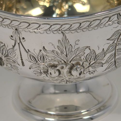 A very pretty Antique Victorian Sterling Silver rose bowl, having a round body with hand-chased swags of floral decoration surrounding two vacant round cartouches on either side, with an applied reed-edged border, a gold-gilt interior, and all sitting on a plain round pedestal foot. This beautiful silver bowl was made by Walker and Hall of Sheffield in 1885. The dimensions of this fine hand-made antique silver bowl are diameter 11 cms (4.25 inches), height 8 cms (3 inches), and it weighs approx. 134g (4.3 troy ounces).