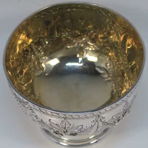A very pretty Antique Victorian Sterling Silver rose bowl, having a round body with hand-chased swags of floral decoration surrounding two vacant round cartouches on either side, with an applied reed-edged border, a gold-gilt interior, and all sitting on a plain round pedestal foot. This beautiful silver bowl was made by Walker and Hall of Sheffield in 1885. The dimensions of this fine hand-made antique silver bowl are diameter 11 cms (4.25 inches), height 8 cms (3 inches), and it weighs approx. 134g (4.3 troy ounces).