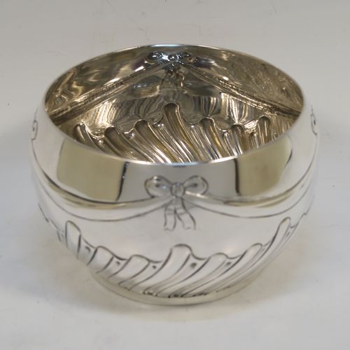 A very pretty Antique Victorian Sterling Silver small Rose bowl, having a round bellied body with hand-chased bows, swags, and half swirl-fluted decoration, and sitting on a flat base. This beautiful antique silver rose bowl was made by the Barnard Brothers of London in 1896. The dimensions of this fine hand-made silver bowl are height 7.5 cms (3 inches), diameter 12 cms (4.75 inches), and it weighs approx. 220g (7 troy ounces).   