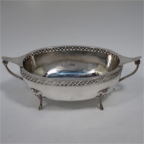 A very unusual and pretty pair of Arts and Crafts style Sterling Silver bowls, having oval bodies with hand-hammered decoration, with hand-pierced and floral borders, two scroll side-handles with flat thumb-pieces, and all sitting on four cast goat hoof feet. Made by A. E. Jones of Birmingham in 1921. The dimensions of these fine hand-made Arts and Crafts silver oval bowls are length 21 cms (8.25 inches), width 11 cms (4.3 inches), height 6.5 cms (2.5 inches), and they weigh a total of approx. 470g (15.2 troy ounces).
