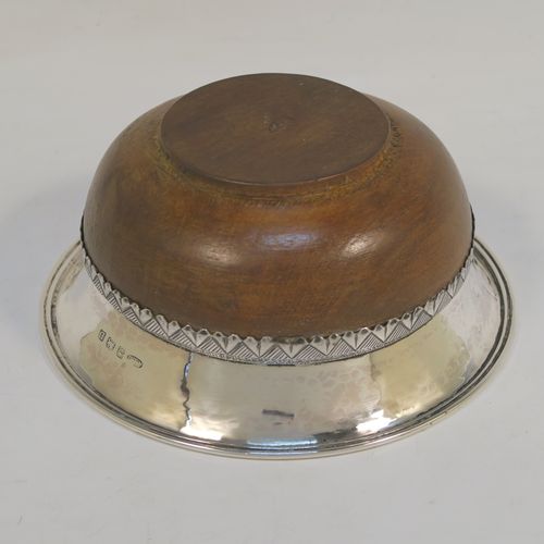 An Arts and Crafts style Sterling Silver & wood Mazer bowl, having a plain round plenished or hand-hammered body, mounted on an Oak base, and having an applied central Celtic style band. This beautiful silver Mazer bowl was made by A. E. Jones of Birmingham in 1928. The dimensions of this fine hand-made wood & silver Mazer bowl are diameter 14 cms (5.5 inches), and height 6.5 cms (2.5 inches). We cannot give a total weight because of the wooden base, but the gauge of silver used is very good.