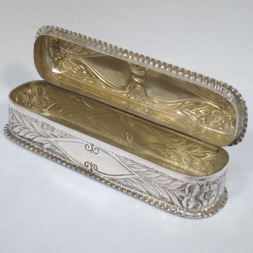 A bold and very pretty Antique Edwardian Sterling Silver Art Nouveau style table box, having a rounded rectangular body with hand-chased floral and scroll decoration, with crimped bead-edged borders and a gold-gilt interior, a hinged lid, and sitting on a flat base. Made by Nathan & Hayes of Birmingham in 1904. The dimensions of this fine hand-made antique silver Art Nouveau style box are length 20 cms (8 inches), width 6 cms (2.3 inches), height 5 cms (2 inches), and it weighs approx. 160g (5.2 troy ounces).