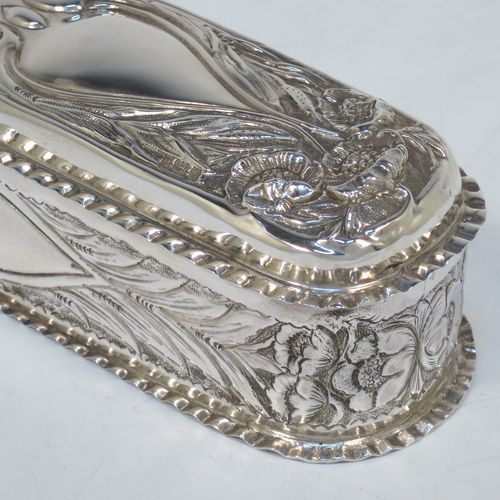 A bold and very pretty Antique Edwardian Sterling Silver Art Nouveau style table box, having a rounded rectangular body with hand-chased floral and scroll decoration, with crimped bead-edged borders and a gold-gilt interior, a hinged lid, and sitting on a flat base. Made by Nathan & Hayes of Birmingham in 1904. The dimensions of this fine hand-made antique silver Art Nouveau style box are length 20 cms (8 inches), width 6 cms (2.3 inches), height 5 cms (2 inches), and it weighs approx. 160g (5.2 troy ounces).