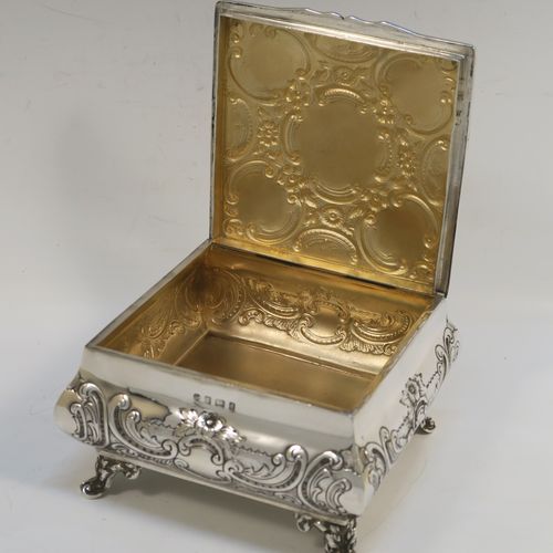 A very pretty Antique Edwardian Sterling Silver table box, having a square bellied body with hand-chased floral and scroll decoration, a hinged lid with matching decoration, a gold gilt interior, and sitting on four cast foliate and scroll feet. This beautiful antique silver box was made by Williams Ltd., of Birmingham in 1903. The dimensions of this fine hand-made silver box are 12.5 cms (5 inches) square, height 7.5 cms (3 inches), and it weighs approx. 328g (10.6 troy ounces).