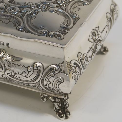 A very pretty Antique Edwardian Sterling Silver table box, having a square bellied body with hand-chased floral and scroll decoration, a hinged lid with matching decoration, a gold gilt interior, and sitting on four cast foliate and scroll feet. This beautiful antique silver box was made by Williams Ltd., of Birmingham in 1903. The dimensions of this fine hand-made silver box are 12.5 cms (5 inches) square, height 7.5 cms (3 inches), and it weighs approx. 328g (10.6 troy ounces).