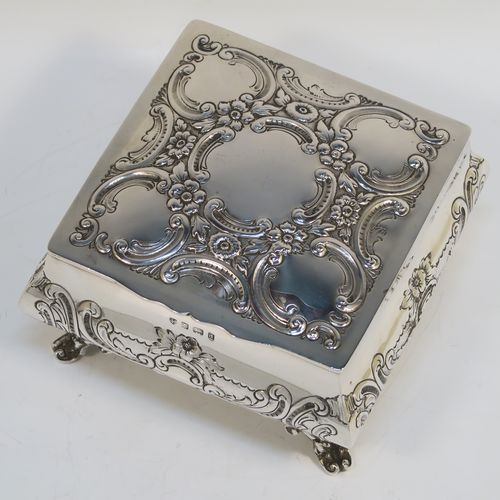 A very pretty Antique Edwardian Sterling Silver table box, having a square bellied body with hand-chased floral and scroll decoration, a hinged lid with matching decoration, a gold gilt interior, and sitting on four cast foliate and scroll feet. This beautiful antique silver box was made by Williams Ltd., of Birmingham in 1903. The dimensions of this fine hand-made silver box are 12.5 cms (5 inches) square, height 7.5 cms (3 inches), and it weighs approx. 328g (10.6 troy ounces).