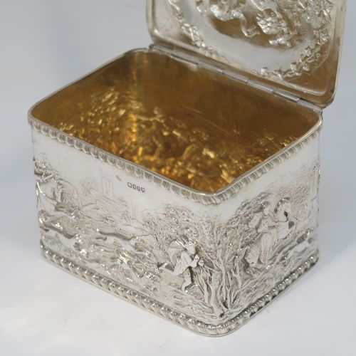 A beautiful Antique Victorian Sterling Silver table box, having a rectangular body with hand-chased figural hunting scenes and applied gadroon borders, a hinged lid with hand-chased grapevine and dancing cherubs, a gold-gilt interior, and sitting on a flat base. This very pretty antique sterling silver box has in importers mark for 1900. The dimensions of this fine hand-made antique silver box are length 9.5 cms (3.75 inches), width 7.5 cms (3 inches), height 6.5 cms (2.6 inches), and it weighs approx. 168g (5.4 troy ounces).