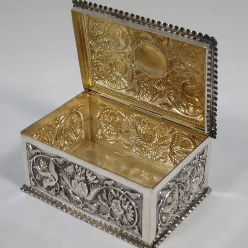 A very pretty Antique Victorian Sterling Silver table box, having a rectangular body with hand-chased floral and scroll decoration, a hinged lid with a vacant cartouche, a gold gilt interior, and sitting on a flat base. Made by Samuel Walton Smith of Birmingham in 1892. The dimensions of this fine hand-made antique silver box are height 6 cms (2.3 inches), length 12 cms (4.75 inches), width 9 cms (3.5 inches), and it weighs approx. 242g (7.8 troy ounces).
