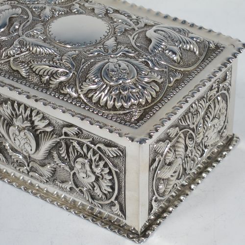 A very pretty Antique Victorian Sterling Silver table box, having a rectangular body with hand-chased floral and scroll decoration, a hinged lid with a vacant cartouche, a gold gilt interior, and sitting on a flat base. Made by Samuel Walton Smith of Birmingham in 1892. The dimensions of this fine hand-made antique silver box are height 6 cms (2.3 inches), length 12 cms (4.75 inches), width 9 cms (3.5 inches), and it weighs approx. 242g (7.8 troy ounces).