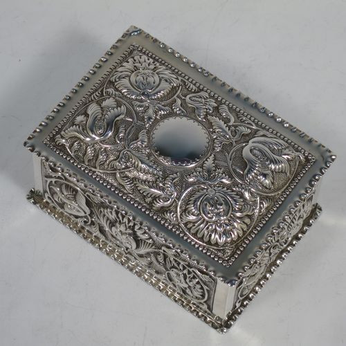 A very pretty Antique Victorian Sterling Silver table box, having a rectangular body with hand-chased floral and scroll decoration, a hinged lid with a vacant cartouche, a gold gilt interior, and sitting on a flat base. Made by Samuel Walton Smith of Birmingham in 1892. The dimensions of this fine hand-made antique silver box are height 6 cms (2.3 inches), length 12 cms (4.75 inches), width 9 cms (3.5 inches), and it weighs approx. 242g (7.8 troy ounces).