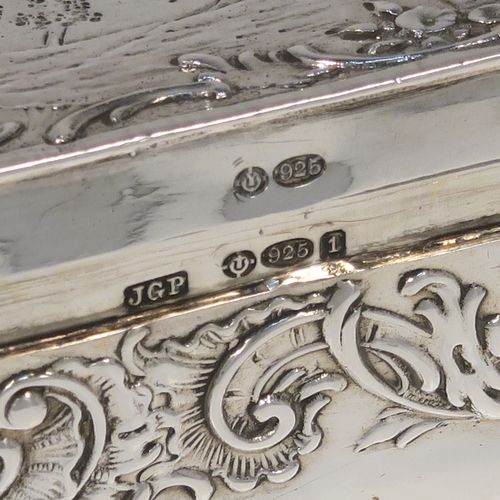 A very pretty Antique Edwardian Sterling Silver table box, having a long rectangular body with rounded ends, with a hinged lid having a hand-chased figural and pastoral scene, a band of floral and scroll decoration on the sides, a gold-gilt interior, and sitting on a flat base. This beautiful silver dressing table box bears a sterling importers mark for John George Piddington of London in 1907. The dimensions of this fine hand-made antique silver table box are length 17 cms (6.75 inches), width 3.5 cms (1.3 inches), height 3 cms (1 inch), and it weighs approx. 151g (4.9 troy ounces).