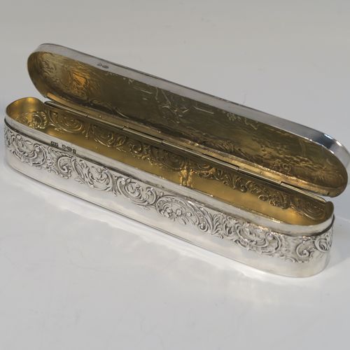 A very pretty Antique Edwardian Sterling Silver table box, having a long rectangular body with rounded ends, with a hinged lid having a hand-chased figural and pastoral scene, a band of floral and scroll decoration on the sides, a gold-gilt interior, and sitting on a flat base. This beautiful silver dressing table box bears a sterling importers mark for John George Piddington of London in 1907. The dimensions of this fine hand-made antique silver table box are length 17 cms (6.75 inches), width 3.5 cms (1.3 inches), height 3 cms (1 inch), and it weighs approx. 151g (4.9 troy ounces).