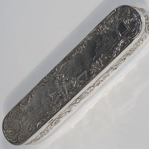 A very pretty Antique Edwardian Sterling Silver table box, having a long rectangular body with rounded ends, with a hinged lid having a hand-chased figural and pastoral scene, a band of floral and scroll decoration on the sides, a gold-gilt interior, and sitting on a flat base. This beautiful silver dressing table box bears a sterling importers mark for John George Piddington of London in 1907. The dimensions of this fine hand-made antique silver table box are length 17 cms (6.75 inches), width 3.5 cms (1.3 inches), height 3 cms (1 inch), and it weighs approx. 151g (4.9 troy ounces).