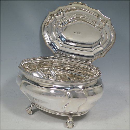 An Antique Edwardian Sterling Silver hand-chased Bonbonnier style heavy table box, having a shaped oval baluster body with a hinged domed lid and thumb-piece, and sitting on four cast scroll feet. Made by David Munsey of London in 1902. The dimensions of this fine hand-made antique silver box are length 20 cms (8 inches), width 14 cms (5.5 inches), height 12.5 cms (5 inches), and it weighs approx. 806g (26 troy ounces).