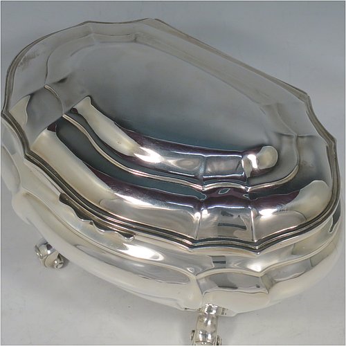 An Antique Edwardian Sterling Silver hand-chased Bonbonnier style heavy table box, having a shaped oval baluster body with a hinged domed lid and thumb-piece, and sitting on four cast scroll feet. Made by David Munsey of London in 1902. The dimensions of this fine hand-made antique silver box are length 20 cms (8 inches), width 14 cms (5.5 inches), height 12.5 cms (5 inches), and it weighs approx. 806g (26 troy ounces).