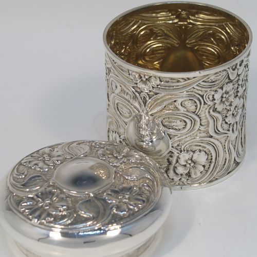 A very pretty Antique Edwardian Sterling Silver Art Nouveau style table box, having a round straight-sided body with hand-chased floral and scroll decoration, a pull-off lid with matching decoration and vacant central cartouche, a gold-gilt interior, and all sitting on a flat base. This beautiful Art Nouveau silver box was made by Synyer and Beddoes of Birmingham in 1903. The dimensions of this fine hand-made antique silver Art Nouveau style box are height 9 cms (3.5 inches), diameter 8 cms (3.25 inches), and it weighs approx. 130g (4.2 troy ounces).