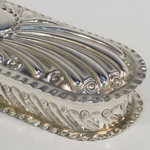 A beautiful Antique Victorian Sterling Silver Art Nouveau style table box, having a rounded rectangular body with hand-chased fluted and scroll decoration, with crimped bead-edged borders and a gold-gilt interior, a hinged lid with a vacant oval cartouche, and sitting on a flat base. This pretty antique silver box was made by Gibson and Langland of London in 1898. The dimensions of this fine hand-made antique silver Art Nouveau style box are length 17.5 cms (7 inches), width 5 cms (2 inches), height 2.5 cms (1 inch), and it weighs approx. 142g (4.6 troy ounces).