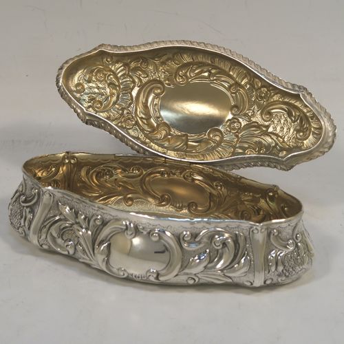 A very pretty Antique Edwardian Sterling Silver Art Nouveau style table box, having a lozenge shaped oval body with a gold-gilt interior hand-chased floral and scroll decoration, a hinged lid with a vacant central oval cartouche, and sitting on a flat base. This beautiful antique silver box was made by John Thompson of Birmingham in 1902. The dimensions of this fine hand-made antique silver Art Nouveau style box are length 13.5 cms (5.25 inches), width 6 cms (2.3 inches), height 4 cms (1.5 inches), and it weighs approx. 88g (2.8 troy ounces).  